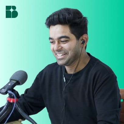 A smiling man wearing a black shirt and earphones sits in front of a microphone, with a teal gradient background and a geometric logo in the top left corner. - Clio Websites | Top Canadian Web Design Company