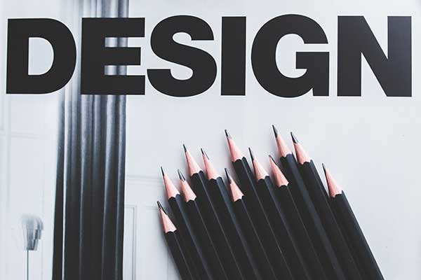 The image features the word "DESIGN" in bold black letters above a collection of black pencils with sharp tips, arranged in a fan-like manner on a light background—perfect inspiration for web design for small businesses. - Clio Websites | Top Canadian Web Design Company