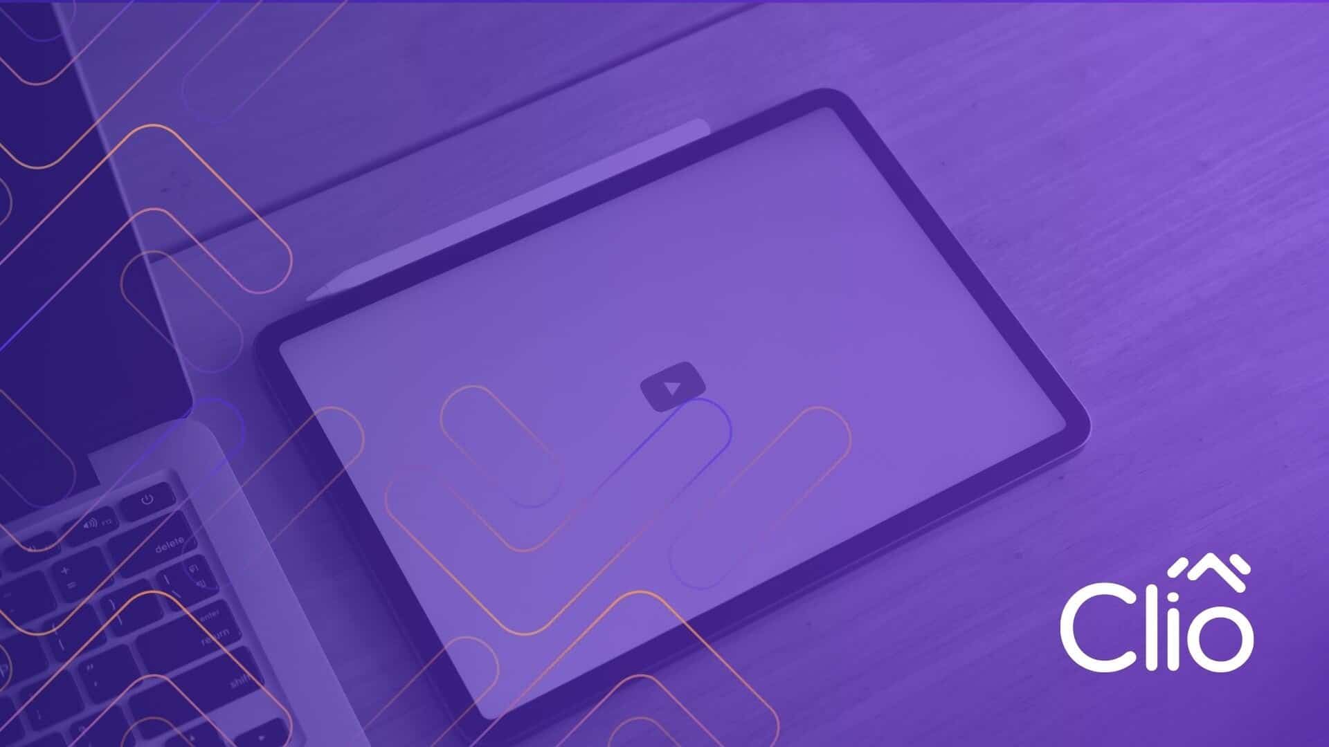 A closed laptop and a tablet with a play button icon sit on a wooden desk, overlaid with a purple filter and abstract lines. The scene hints at how to add YouTube videos to WordPress. The Clio logo appears in the bottom right corner. - Clio Websites | Top Canadian Web Design Company