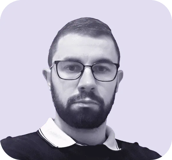 A man with a beard and glasses looks at the camera, embodying the professionalism you'd expect from Clio websites. He is wearing a collared shirt under a sweater, set against a solid blue background. - Clio Websites | Top Canadian Web Design Company