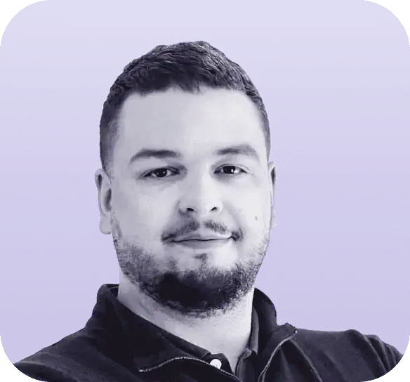 Portrait of a man with short hair and a beard against a gradient purple background, reminiscent of the About pages on Clio websites. He is wearing a dark collared shirt and smiling slightly. - Clio Websites | Top Canadian Web Design Company